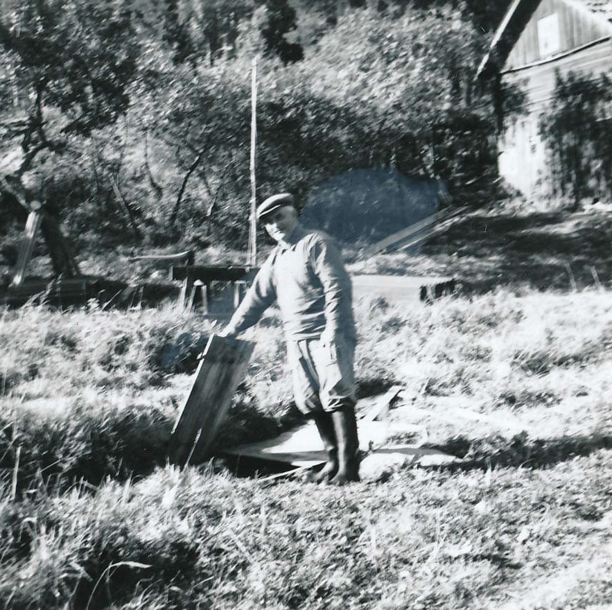 Fotografi av man som står på gård och håller upp ett trälock tillhörande en brunn.